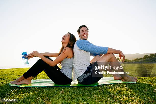 couple sitting on yoga mat in park - mann wasser trinken sport stock-fotos und bilder