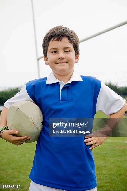 hispanic boy holding rugby ball on field - ラグビーボール ストックフォトと画像