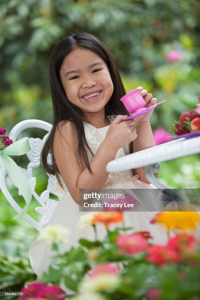 Mixed race girl having tea party in backyard