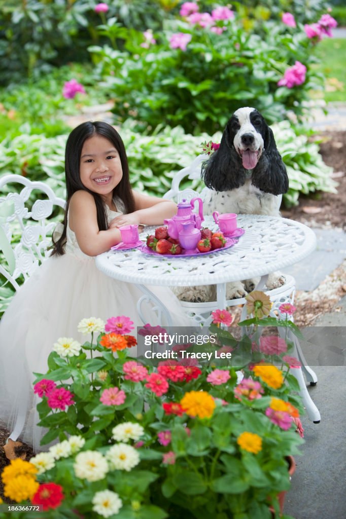 Mixed race girl and dog having tea party in backyard