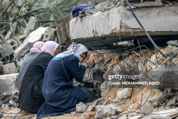 Palestinian women cry where a relative is believed to be trapped in debris following Israeli bombardment in Rafah in the southern Gaza Strip on...