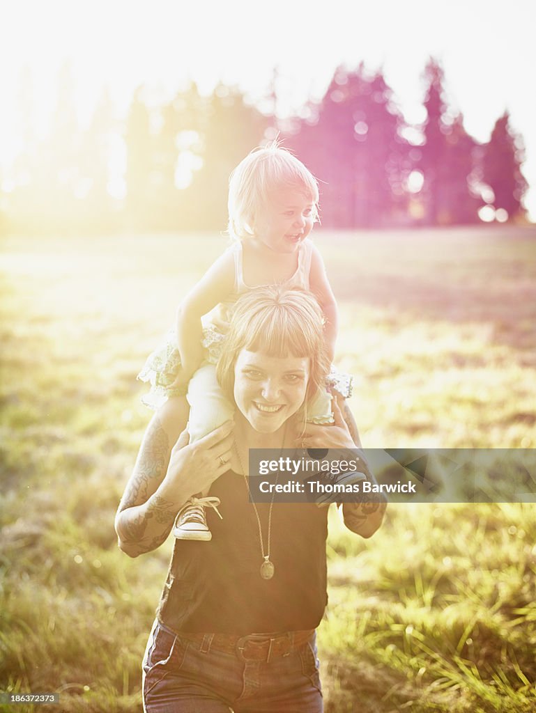 Mother standing holding toddler on shoulders