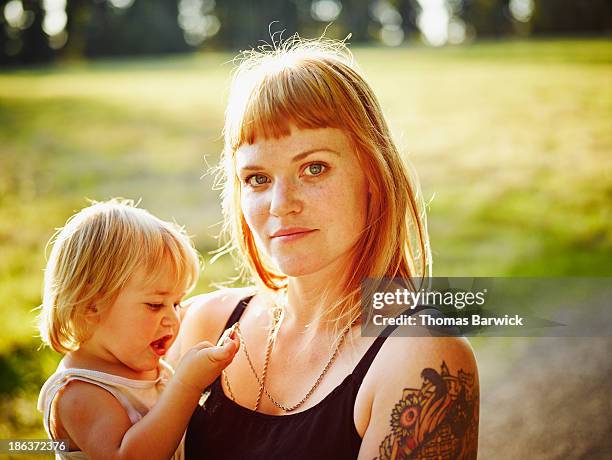 mother holding toddler in field at sunset - contemplation family stock-fotos und bilder