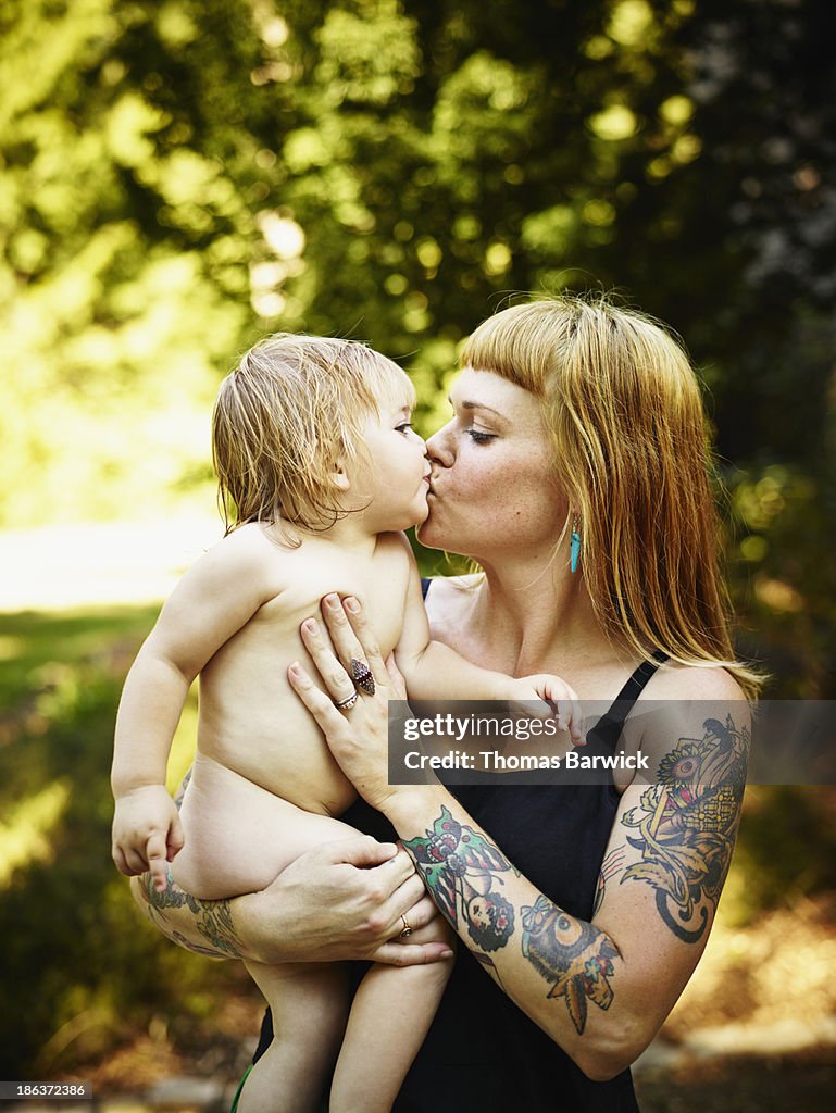 Toddler daughter being kissed and held by mother