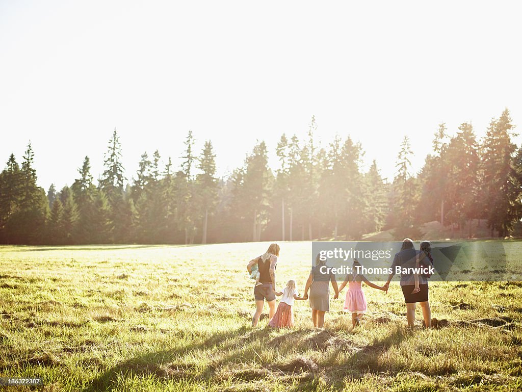Mothers walking through field with daughters