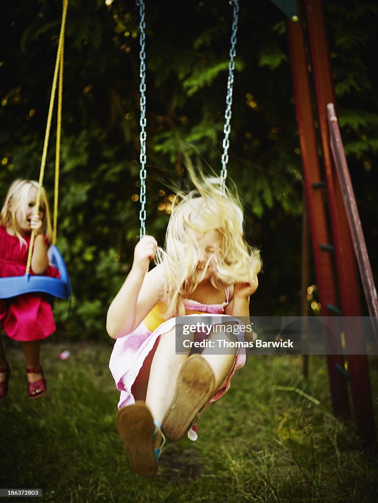 Sisters swinging together on swing set