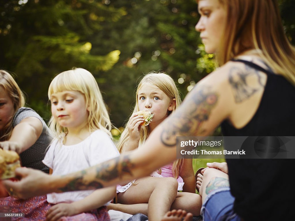 Young girls and mom sitting on blanket outdoors