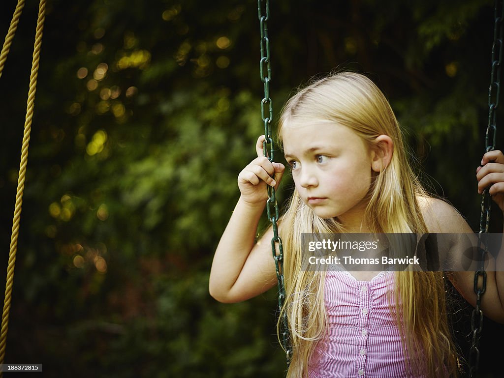 Young girl sitting on swing looking out
