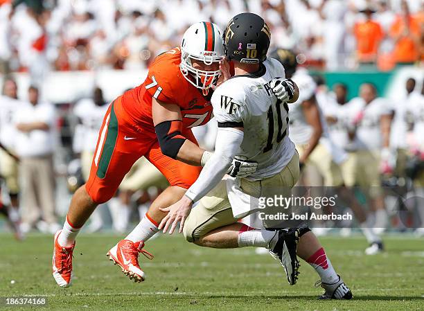 Anthony Chickillo of the Miami Hurricanes hits Tanner Price of the Wake Forest Demon Deacons after Price released the ball on October 26, 2013 at Sun...