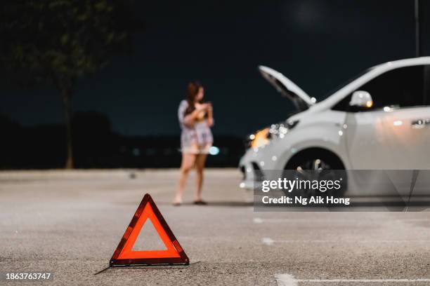 a lady's car brake down at open space parking lot and waiting for help - warning triangle stock pictures, royalty-free photos & images