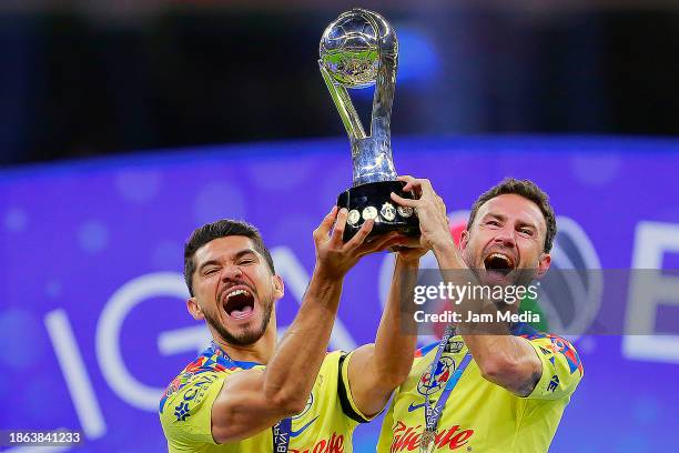 Henry Martin and Miguel Layun of America lift the championship trophy after winning the final second leg match between America and Tigres UANL as...