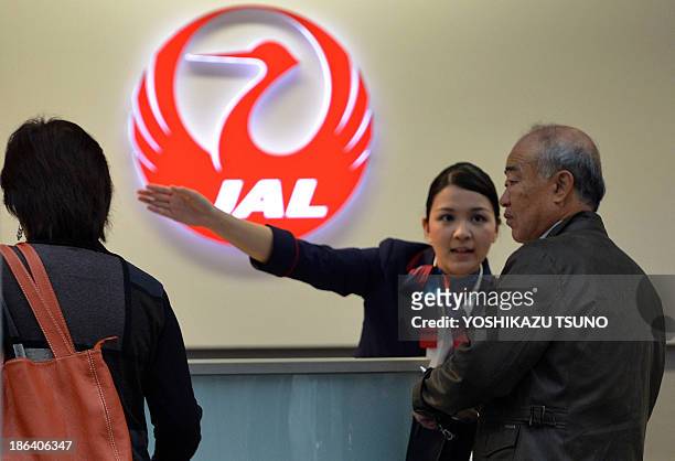 In a picture taken on October 30 a Japan Airlines ground staff employee guides a passenger at a check-in couter at Tokyo's Haneda airport. Japan...