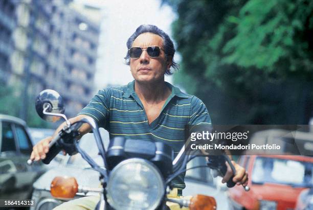 Italian singer-songwriter, stand-up comedian and actor Enzo Jannacci driving a motorbike. 1985.