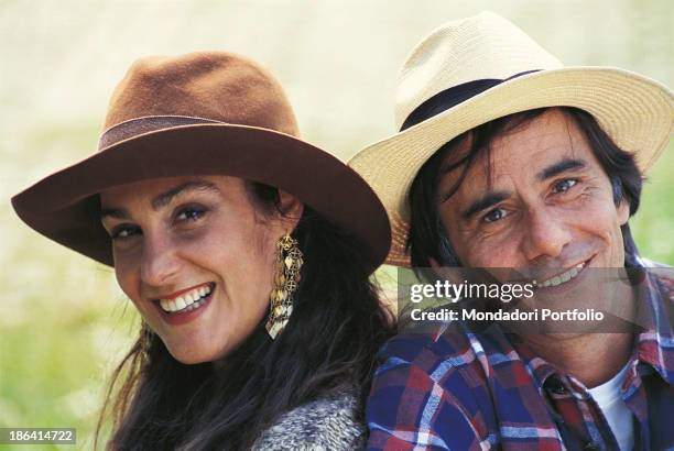Italian singer-songwriter and writer Roberto Vecchioni smiling on a meadow with his wife, Italian journalist Daria Colombo. Italy, 1991.