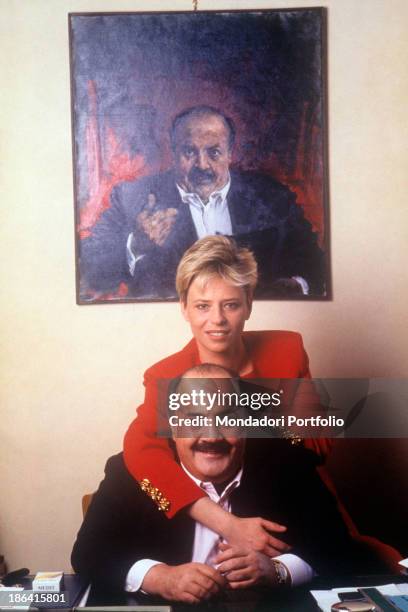 Italian Tv presenter Maria De Filippi hugging her future husband and Italian journalist and TV host Maurizio Costanzo. Behind them, a painting...