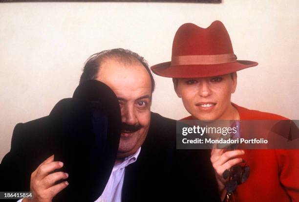 Italian journalist and TV host Maurizio Costanzo hiding himself behind a hat beside his wife and Italian TV presenter Maria De Filippi holding a...