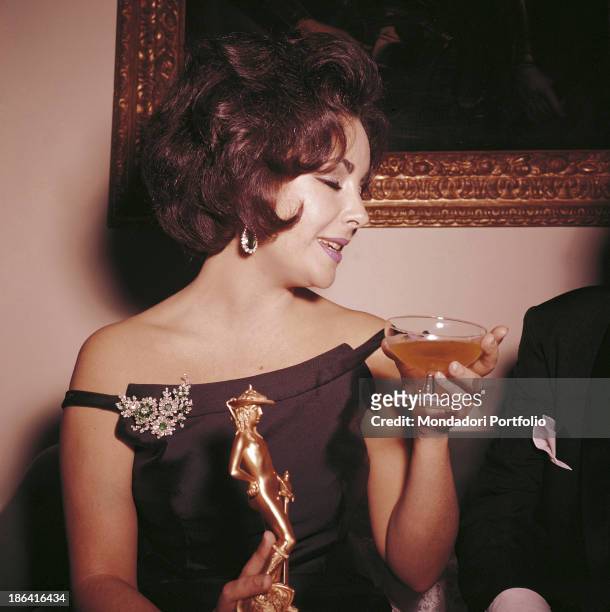 British-born American actress Elizabeth Taylor having a drink holding the David di Donatello Award in her hand, won for her performance in the film...