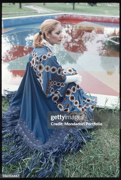 Italian singer Mia Martini posing crouching in the park of the Enzo Pagani Museum next to a fountain. Castellanza, 1972.