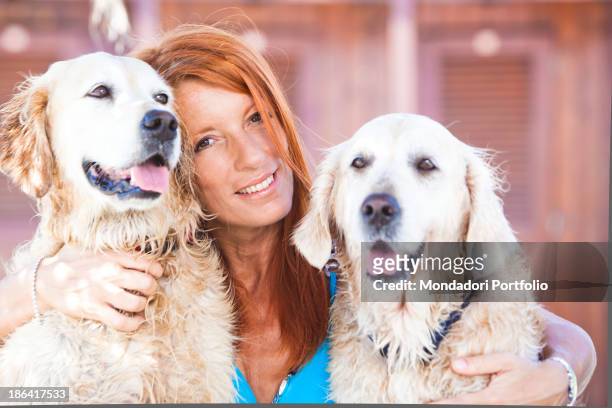 Italian politician and animalist Michela Vittoria Brambilla hugging two Golden Retriever dogs in front of the bathing-huts at the lido Bau Bau...