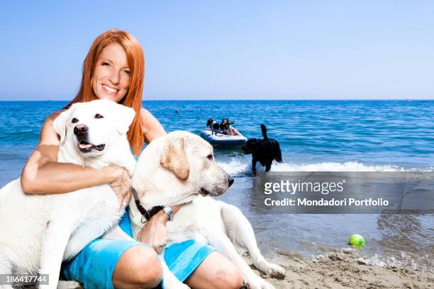 Italian politician and animalist Michela Vittoria Brambilla hugging two Labrador dogs by the sea at the lido Bau Bau Village. Albisola Marina, 22nd...