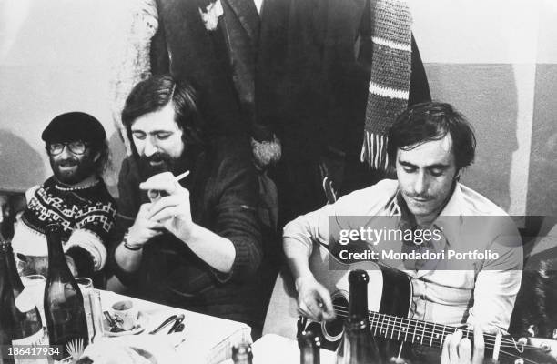 Italian singer-songwriter and writer Roberto Vecchioni playing the guitar beside Italian singer-songwriters Lucio Dalla and Francesco Guccini. Italy,...