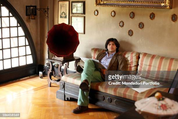 Vittorio Sgarbi's son Carlo Sgarbi Brenner sitting on the sofa in the livingroom of Villa Banfi. Vimercate, 2000s.