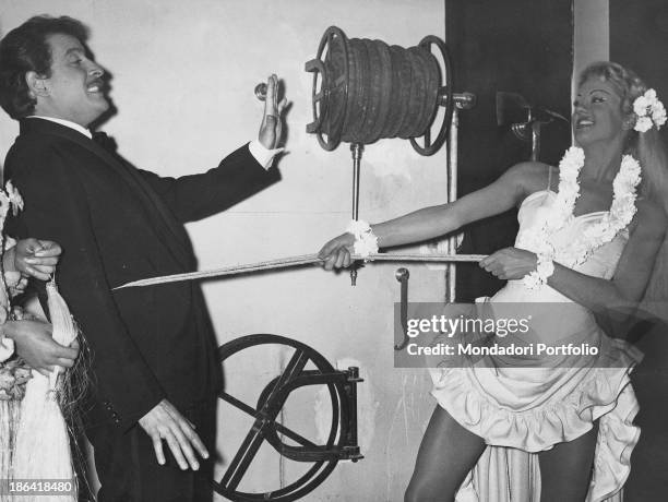 Young woman catching Italian singer-songwriter and actor Domenico Modugno with a lasso and pulling him. 1959.