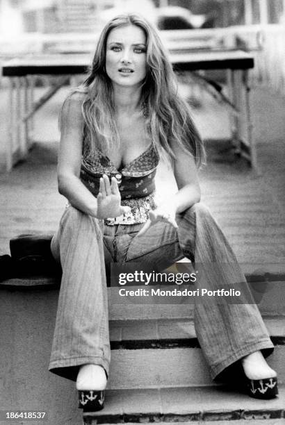 The German actress Barbara Bouchet seated on the steps of a stairs, in the background there is a ping pong table; she's a muse for the cinema, with...