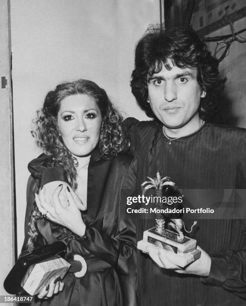 Italian singer Toto Cutugno hugging his wife Carla and holding the prize won with the song Solo noi at 30th Sanremo Music Festival. Sanremo, February...