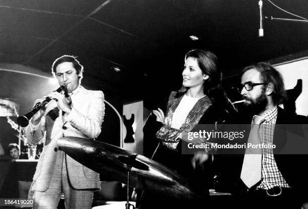 The TV announcer Gabriella Farinon and the musician and journalist Fabrizio Zampa, sitting at the drums listen carefully to Renzo Arbore who...