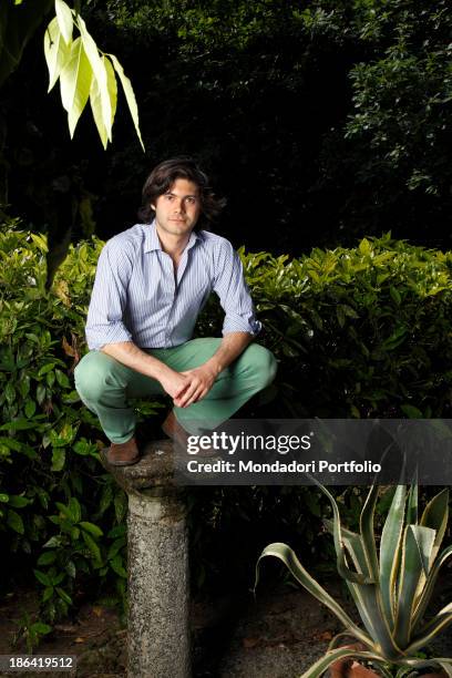 Vittorio Sgarbi's son Carlo Sgarbi Brenner crouched on a column in the garden of Villa Banfi. Vimercate, 2000s.