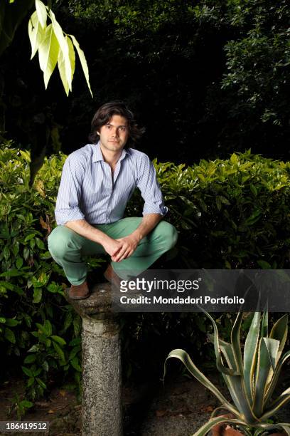 Vittorio Sgarbi's son Carlo Sgarbi Brenner crouched on a column in the garden of Villa Banfi. Vimercate, 2000s.