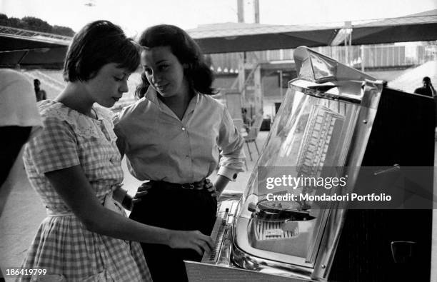 The two sisters and swimming champions Daniela, on the left, and Anna Beneck get distracted with the music of a juke box; both are going to take part...