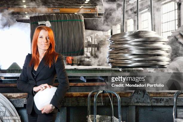 Italian entrepreneur and politician Michela Vittoria Brambilla posing with a hard hat in her hands in front of some steel wires in stack at...