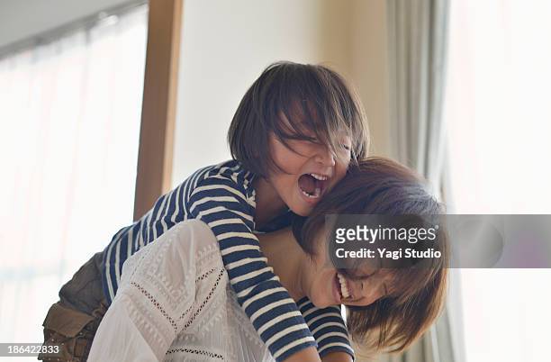 daughter playing with mother in the room - offspring stock-fotos und bilder