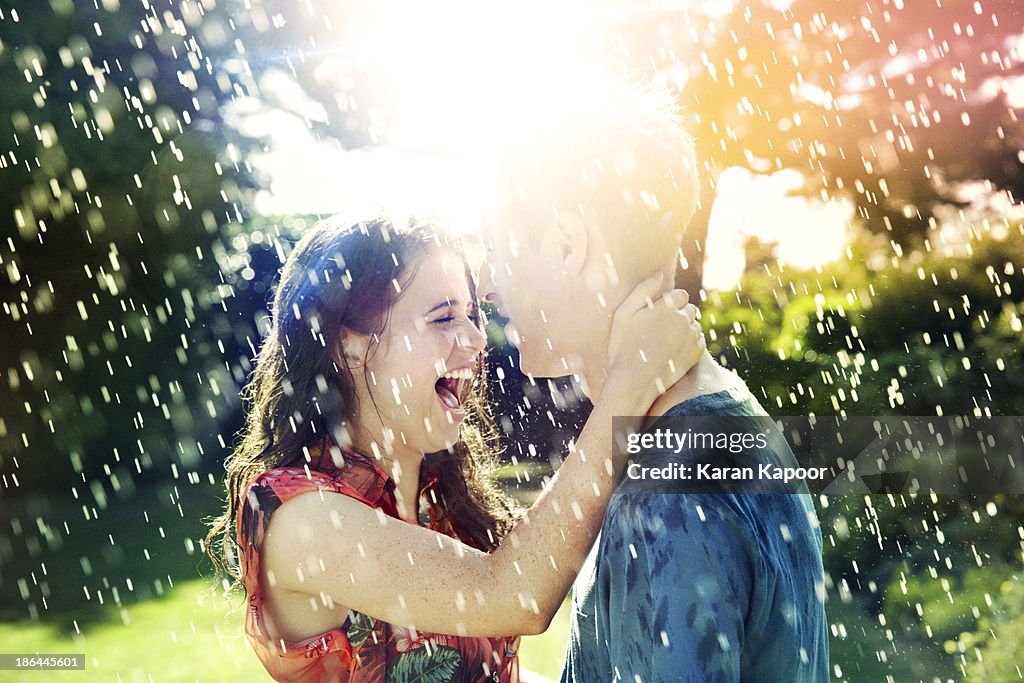 Teenage couple laughing in rain