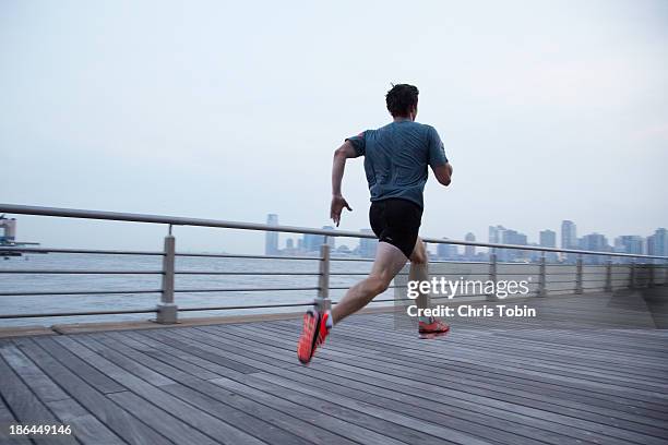 man running on pier in front of city skyline - urban areas　water front stockfoto's en -beelden