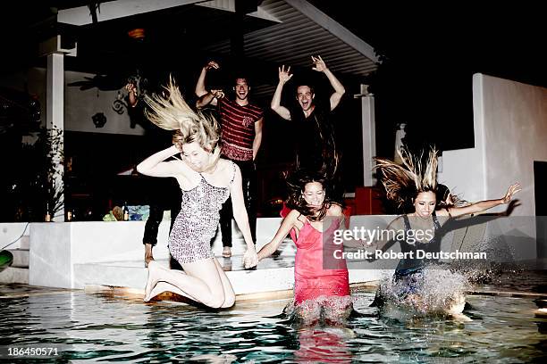 friends dressed up jumping into the pool at night. - glamour fotografías e imágenes de stock