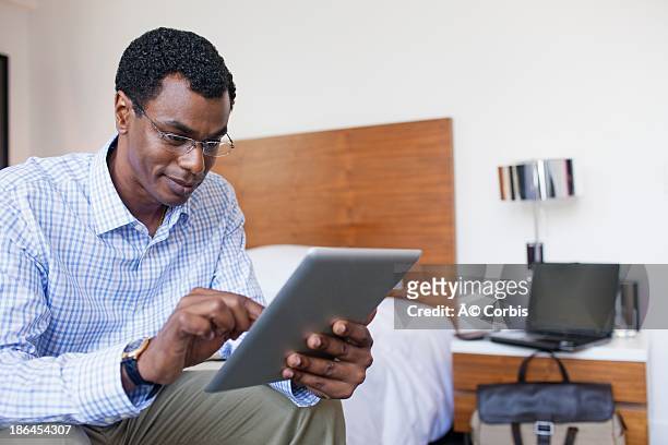 business man working on tablet in hotel room - man in suite holding tablet stockfoto's en -beelden