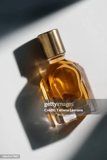 perfume bottle casting shadows on the white background making beautiful illuminating effect of caustic. perfume and beauty cosmetics industry. aromatherapy, spa, wellness concept. commercial photo with copy space - fragrance launch stock-fotos und bilder