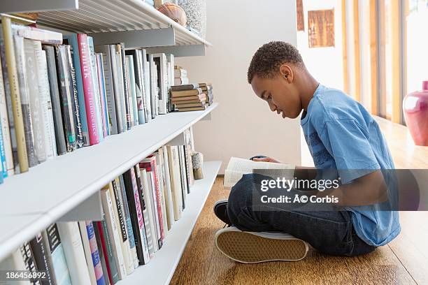 boy (10-11) reading book at home - boy 10 11 stock pictures, royalty-free photos & images