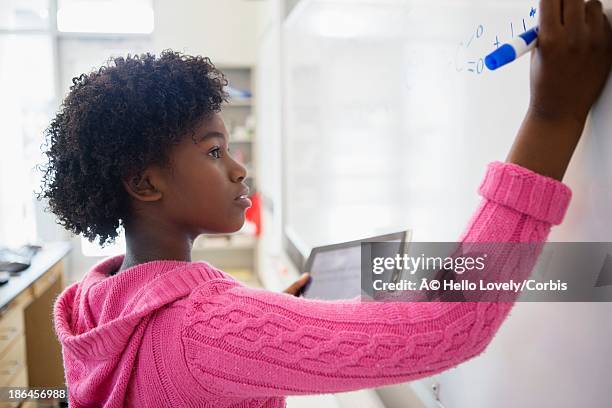 teenage girl (13-15) writing on whiteboard - adolescent africain stock pictures, royalty-free photos & images