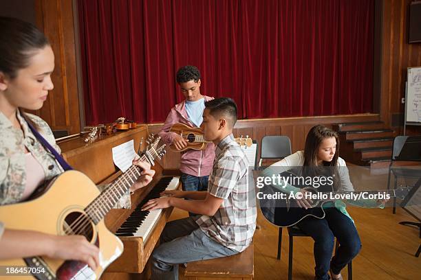 four pupils (16-17) playing musical instruments during music lesson - adolescent africain stock pictures, royalty-free photos & images