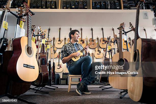 man testing guitar in shop - guitar shop stock pictures, royalty-free photos & images