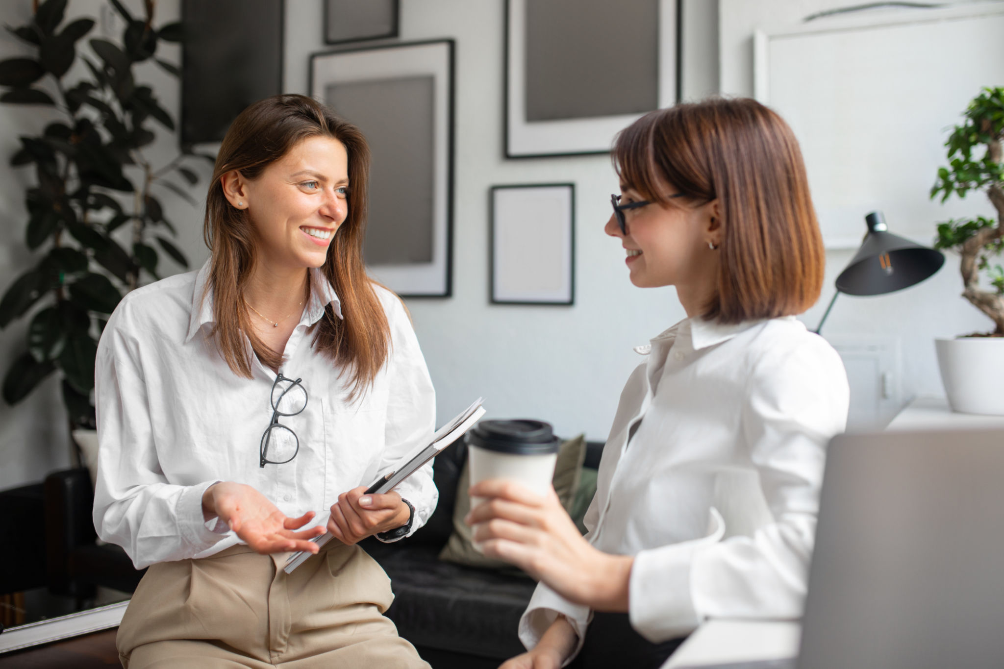 Cheerful lady coworkers enjoying coffee break, two businesswomen talking, meeting and chatting in office Cheerful lady coworkers enjoying coffee break, two businesswomen talking, meeting and chatting in office