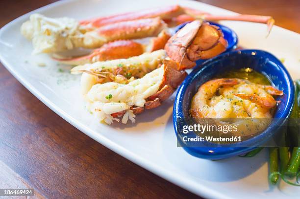 seafood dish with crab legs, lobster tail and shrimps in butter sauce - crab leg stock pictures, royalty-free photos & images