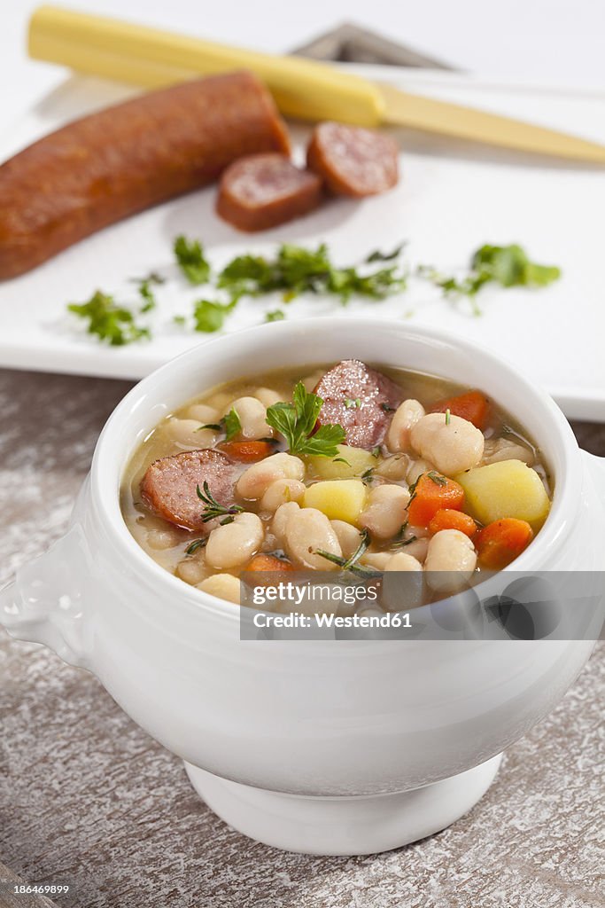 Bowl of white bean soup with smoked sausage, close up