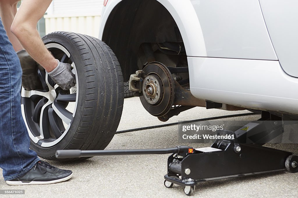 Germany, Bavaria, Kaufbeuren, Mature man changing car tire