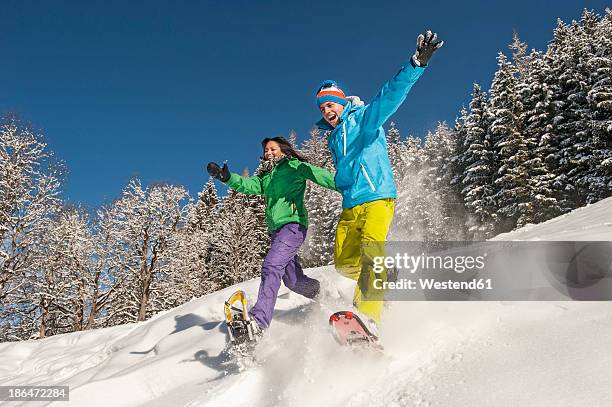 austria, salzburg, young woman and man snowshoeing at altenmarkt zauchensee - racchetta da neve attrezzatura sportiva foto e immagini stock