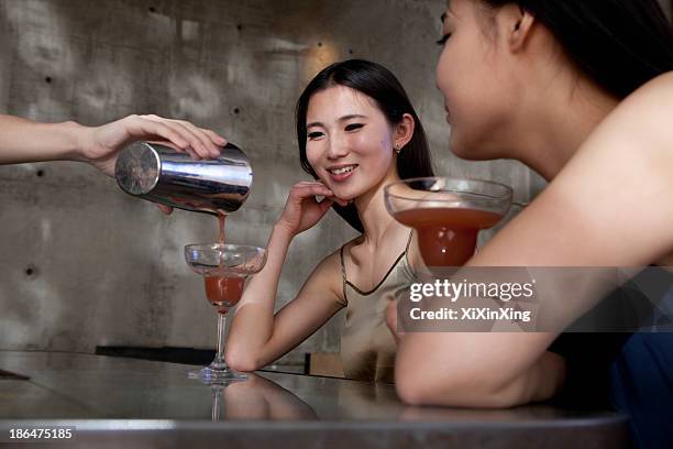 young women having cocktails, sitting at the bar counter - cocktail counter stock-fotos und bilder